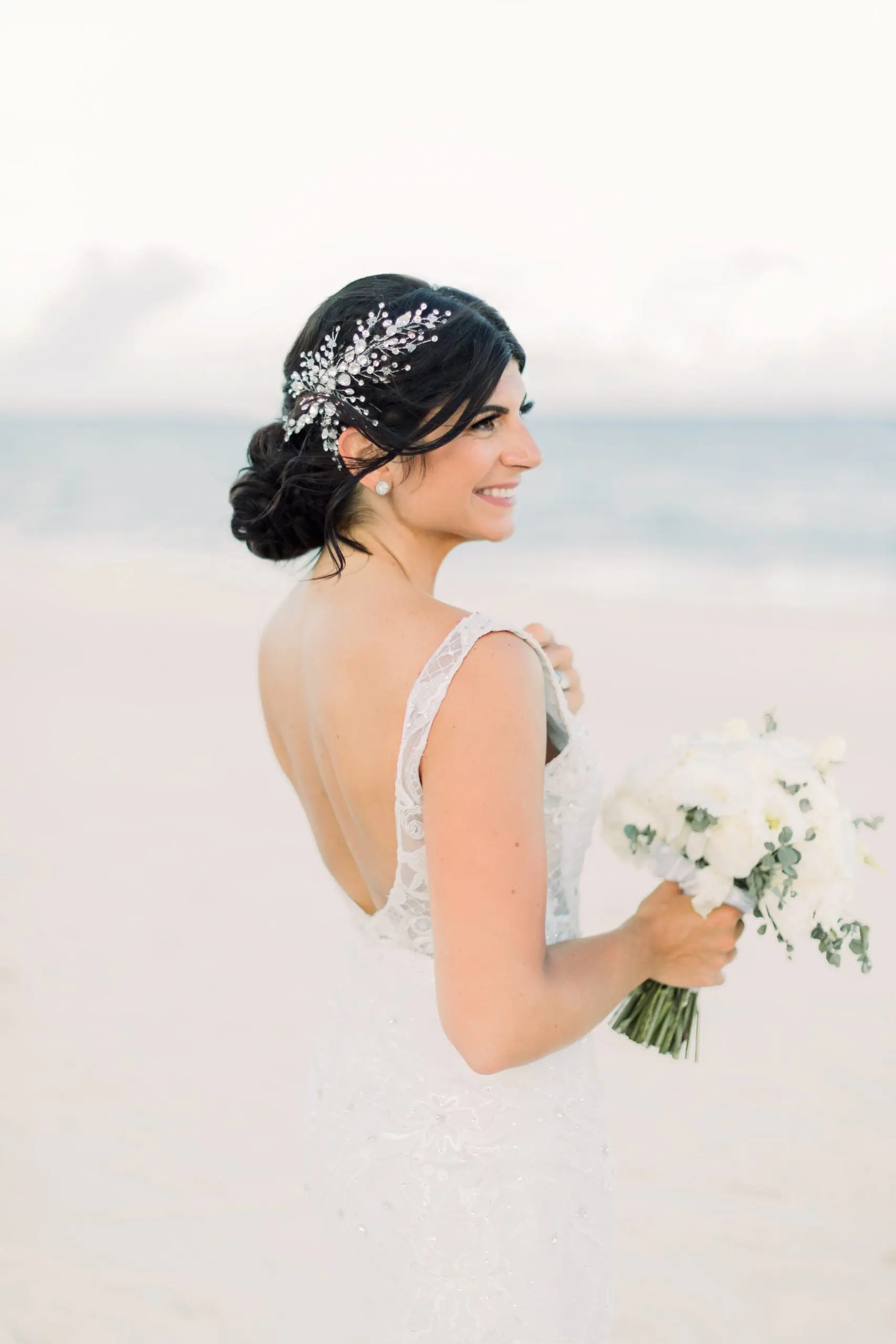 bride poses at the Playa Linda beach inn Playa del Carmen, Iberostar Riviera Maya. white gown, elegant bridal hairstyle and glowy makeup